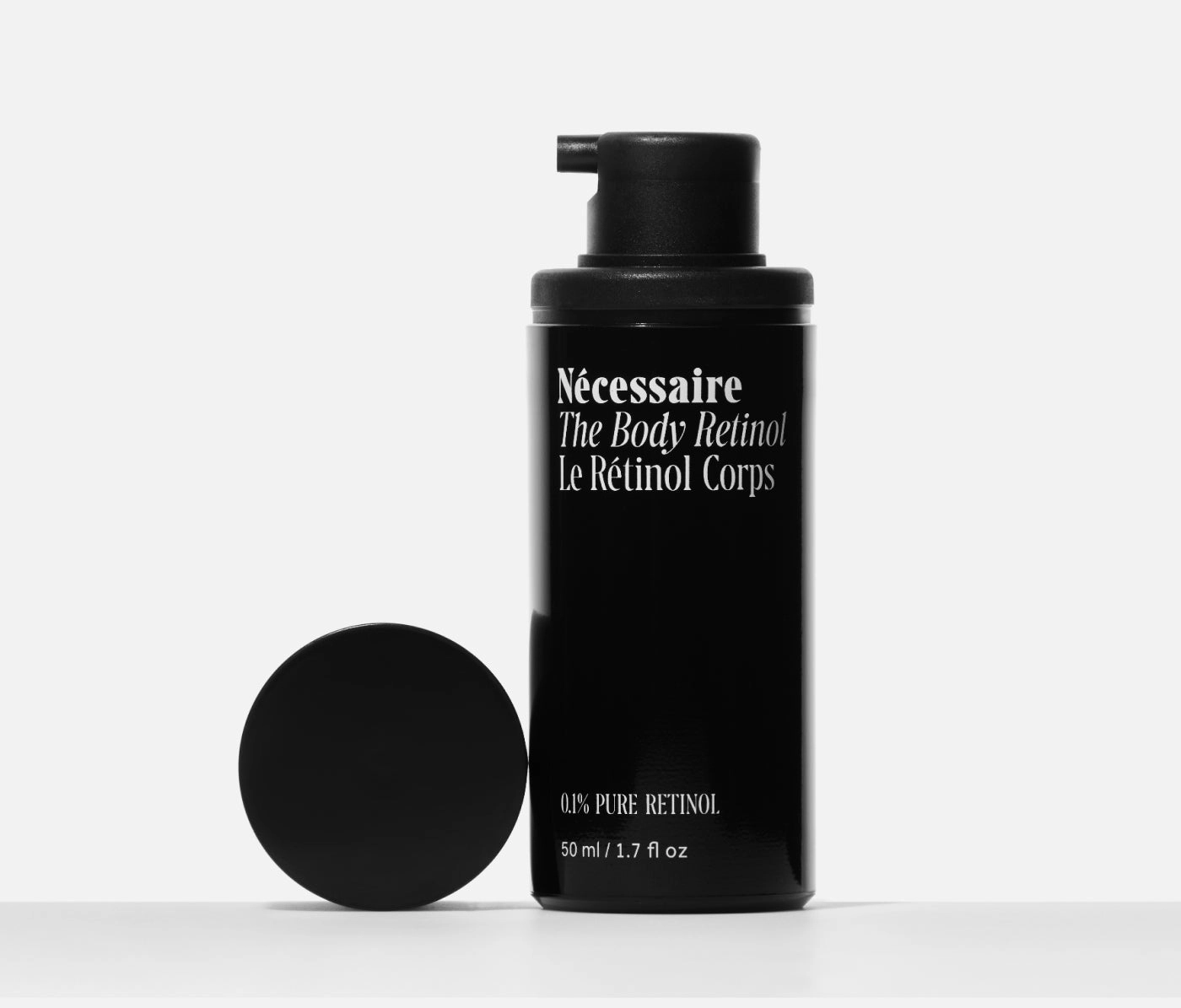 The Body Retinol pump bottle with its round black cap lying beside it