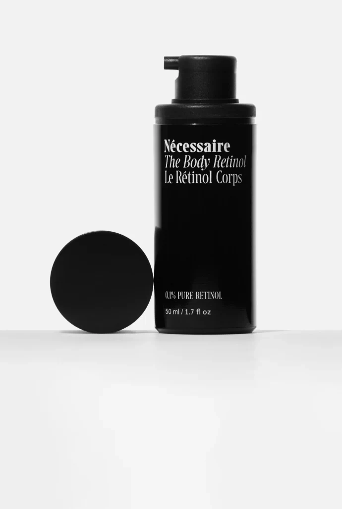 The Body Retinol pump bottle and cap on a white ground, tall crop
